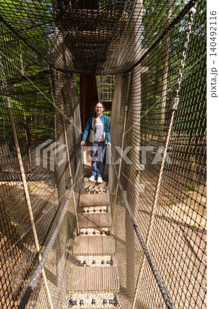 Child exploring rope tunnel in forest adventure park 140492116