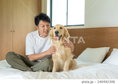 ベッドの上でゴールデンレトリバーとふれあう男性 ベッドの上でゴールデンレトリバーとふれあう男性 140492306
