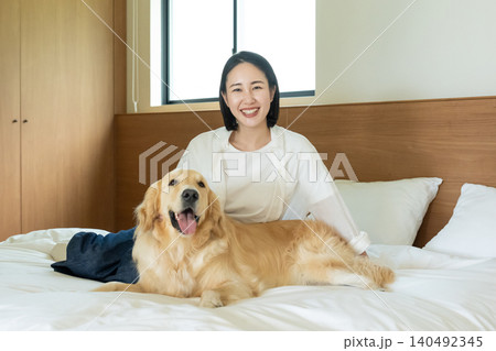 寝室のベッドで愛犬と笑顔の女性 140492345
