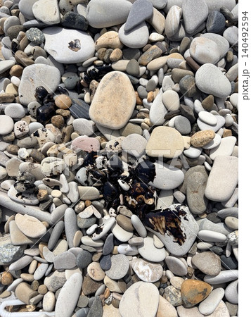 Coastal pebbles smeared with black fuel oil or drops of oil. Pollution of nature Coastal pebbles smeared with black fuel oil or drops of oil. Pollution of nature 140492594