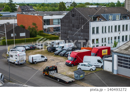 Neuss, Germany, 10.06.2026 - High angle view of a commercial parking lot with delivery vans, trucks, tow truck and motorhomes near an office building in a European industrial area Neuss, Germany, 10.06.2026 - High angle view of a commercial parking lot with delivery vans, trucks, tow truck and motorhomes near an office building in a European industrial area 140493272