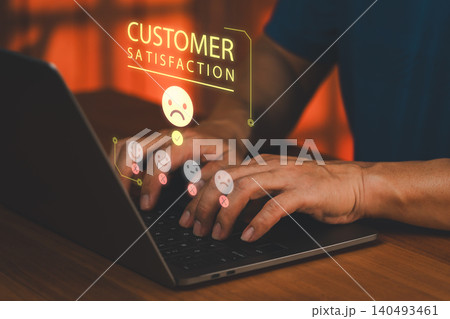 Man typing on laptop giving negative customer satisfaction feedback. Virtual hologram showing sad face rating for poor service experience. 140493461