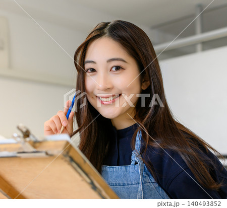 美術予備校で絵を描く笑顔の女子学生 美術予備校で絵を描く笑顔の女子学生 140493852