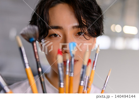 絵筆越しに見つめる美術学生、制作への集中 絵筆越しに見つめる美術学生、制作への集中 140494144