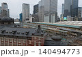 駅の駅舎と高層ビルの谷間を走る列車 140494773