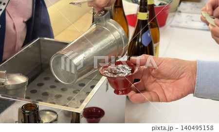 熱燗を赤い盃に注ぐ日本酒の提供シーン 熱燗を赤い盃に注ぐ日本酒の提供シーン 140495158