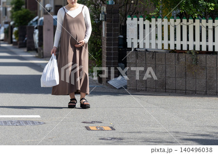 買物から帰ってきた、レジ袋を持って住宅地を歩いている妊婦 買物から帰ってきた、レジ袋を持って住宅地を歩いている妊婦 140496038