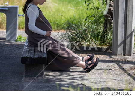 日陰のベンチで休憩している臨月の妊婦 日陰のベンチで休憩している臨月の妊婦 140496166