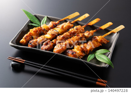 黒い皿に盛り付けられた香ばしい焼き鳥のタレ 箸と箸置きが添えられた居酒屋メニュー 140497228