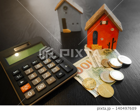 Coin stack on calculator with model house, business finance investment income, salary payment tax, stock market economy deposit profit currency statistics earnings. Coin stack on calculator with model house, business finance investment income, salary payment tax, stock market economy deposit profit currency statistics earnings. 140497689