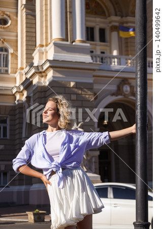 Woman poses confidently near a historic building under sunlight Woman poses confidently near a historic building under sunlight 140499642