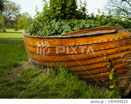 View of wooden rowing boat in lush green tree parkland View of wooden rowing boat in lush green tree parkland 140499820