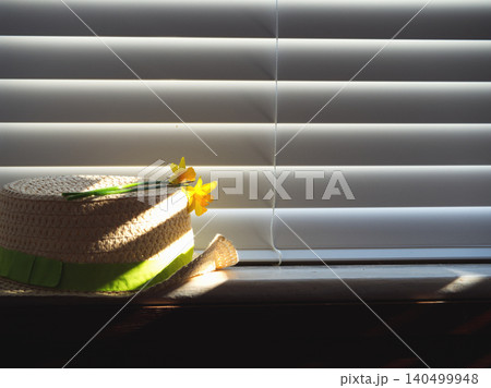 Easter bonnet straw with daffodil flowers in dappled sunlight Easter bonnet straw with daffodil flowers in dappled sunlight 140499948