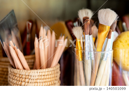 Artist paintbrush with pencils, painting spatula and sponge in glass holder in art workshop studio Artist paintbrush with pencils, painting spatula and sponge in glass holder in art workshop studio 140501099