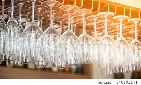 Empty wine glasses hang upside down on the rack over bar counter 140501141