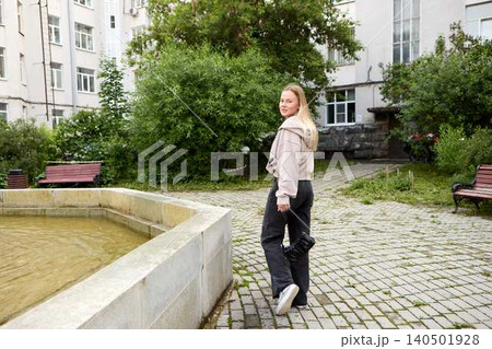 Young woman walking in urban courtyard looking back Young woman walking in urban courtyard looking back 140501928
