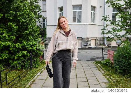 Young woman walking urban path smiling confidently Young woman walking urban path smiling confidently 140501941