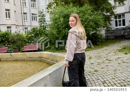 Young woman walking in urban courtyard looking back Young woman walking in urban courtyard looking back 140501953