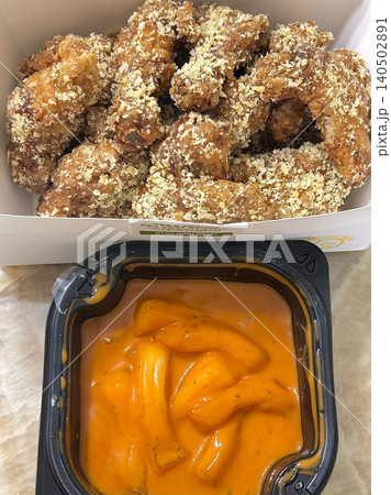 Crispy Korean fried chicken with golden coating served alongside spicy tteokbokki with chewy rice cakes in rich red sauce, creating a flavorful combination of crunchy and savory textures 140502891