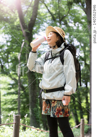 トレッキングが楽しい笑顔のアクティブな女性 水分補給で水を飲む初夏のアウトドアイメージ トレッキングが楽しい笑顔のアクティブな女性 水分補給で水を飲む初夏のアウトドアイメージ 140502946