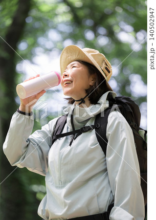 トレッキングが楽しい笑顔のアクティブな女性 水分補給で水を飲む初夏のアウトドアイメージ トレッキングが楽しい笑顔のアクティブな女性 水分補給で水を飲む初夏のアウトドアイメージ 140502947