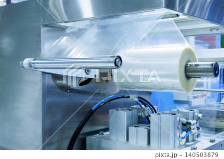 plastic packaging film on the automatic packing machine in food product factory. industrial and technology concept. 140503879
