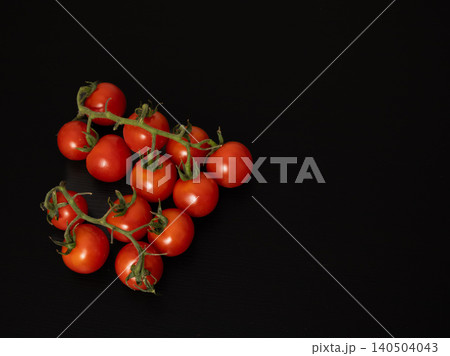 Vine of cherry tomatoes isolated on black background with copy space Vine of cherry tomatoes isolated on black background with copy space 140504043