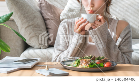 リビングテーブルで食事をするおしゃれな若いアジア人女性 140504400