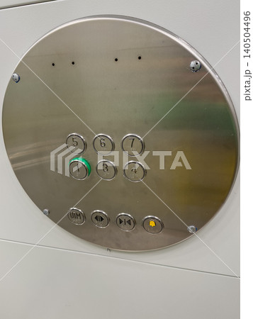 A Close-Up View of an Elevator Control Panel Featuring Numeric Buttons and Function Controls in a Metallic Finish 140504496