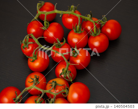 Cherry tomatoes on the vine on dark table surface with copy space 140504503