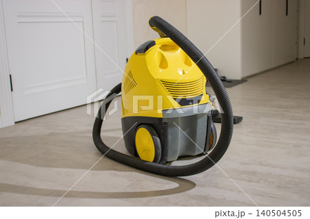 A Bright Yellow Vacuum Cleaner Positioned on a Clean, Light-Colored Floor in a Minimalist Indoor Setting, Highlighting Modern Cleaning Tools A Bright Yellow Vacuum Cleaner Positioned on a Clean, Light-Colored Floor in a Minimalist Indoor Setting, Highlighting Modern Cleaning Tools 140504505