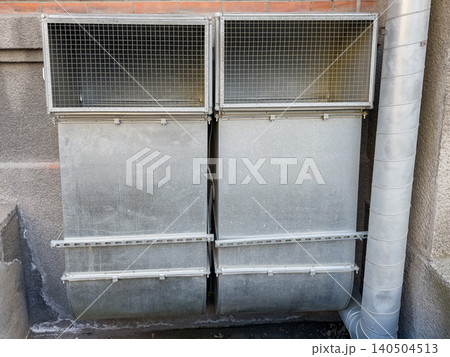 Industrial Ventilation System with Dual Exhaust Hoods and Metal Ductwork Installed Against a Concrete Wall 140504513