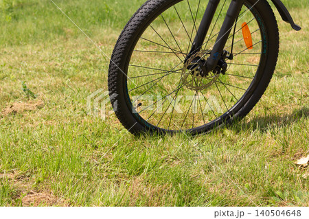 Dark blue mountain bicycle on the grass near a fence. Summer outdoor activity Dark blue mountain bicycle on the grass near a fence. Summer outdoor activity 140504648