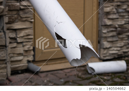 Damaged Drainpipe with Cracks and Holes Indicating Water Leakage from the Building's Exterior Structure 140504662