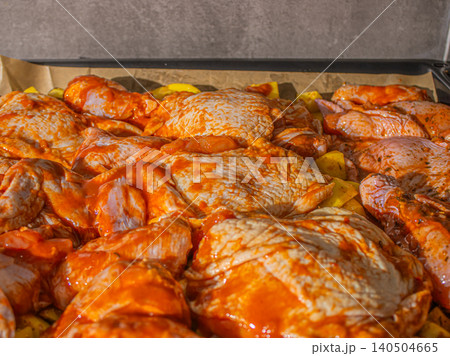 An Array of Flavorful Marinated Chicken Thighs Ready for Grilling, Surrounded by Wholesome Potatoes in a Rustic Kitchen Setting 140504665