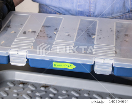 Plastic organizer box labeled cucumber with dirt on lid, close-up of compartment storage on car seat 140504694
