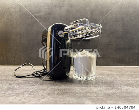 Electric Mixer with Mixing Attachments Next to a Glass of Flour on a Modern Kitchen Countertop Electric Mixer with Mixing Attachments Next to a Glass of Flour on a Modern Kitchen Countertop 140504704