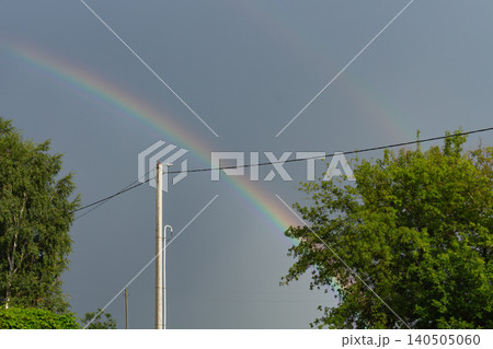Vibrant double rainbow arching over green summer trees and power line pole Vibrant double rainbow arching over green summer trees and power line pole 140505060