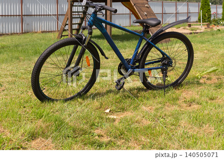 Close-up of a blue mountain bike with muddy fenders on a green lawn outdoors Close-up of a blue mountain bike with muddy fenders on a green lawn outdoors 140505071