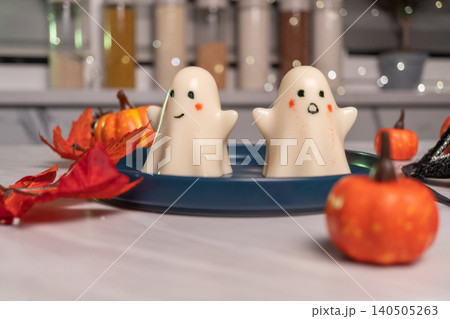 Cute ghost figurines and mini pumpkins on blue plate in autumn kitchen 140505263