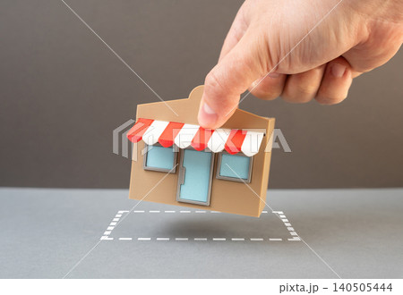A hand puts a store in the right place symbolizing business expansion and planning. Opening a new store, leasing land and selecting a strategic retail location. 140505444