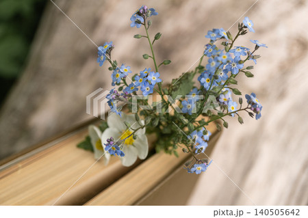Delicate blue flowers placed on old book edge outdoors 140505642
