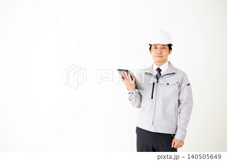 タブレットを持つグレーの作業着のミドル男性ビジネスマン白バック タブレットを持つグレーの作業着のミドル男性ビジネスマン白バック 140505649