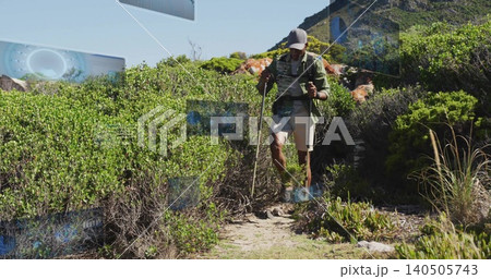 Descending male hiker wearing cap jacket, navigating narrow coastal trail with backpack and poles Descending male hiker wearing cap jacket, navigating narrow coastal trail with backpack and poles 140505743