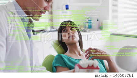Whitecoat dentist checking teal-top patient in dental chair holding red-white model, green overlay 140505761