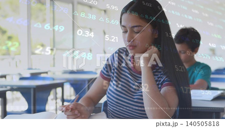 Studying teen girl wearing striped tee sitting in classroom, reading workbook, data overlay 140505818