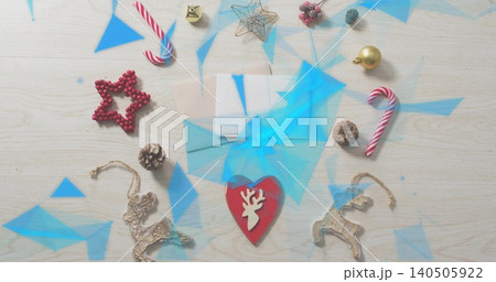 Resting red heart reindeer-cutout ornament on pale envelope on wood tabletop, showing blue overlays Resting red heart reindeer-cutout ornament on pale envelope on wood tabletop, showing blue overlays 140505922