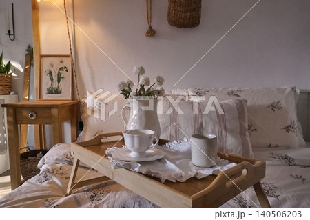 Cozy Bedroom Setting with Breakfast Tray, Fresh Flowers, and Soft Bedding for Relaxation 140506203
