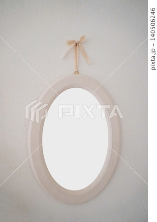 Elegant Oval Mirror Hanging on White Wall with Decorative Bow for Stylish Home Interiors Elegant Oval Mirror Hanging on White Wall with Decorative Bow for Stylish Home Interiors 140506246