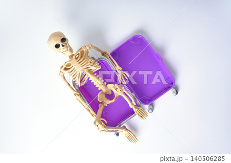 Top view of a Playful Skeleton Relaxing Inside a Bright Purple Suitcase on a White Background Top view of a Playful Skeleton Relaxing Inside a Bright Purple Suitcase on a White Background 140506285